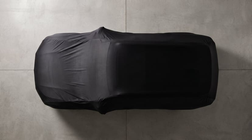 Top-down view of a black stretch cover fitted closely over an SUV on a concrete garage floor.