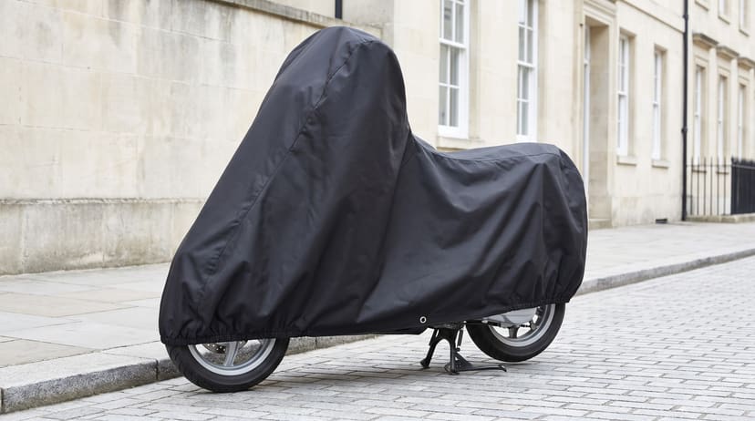 A scooter under a matte black cover on a terraced street.