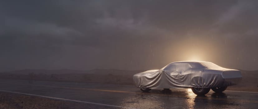Silver cover on a modern muscle car beaded with rain on a wet desert road at dusk
