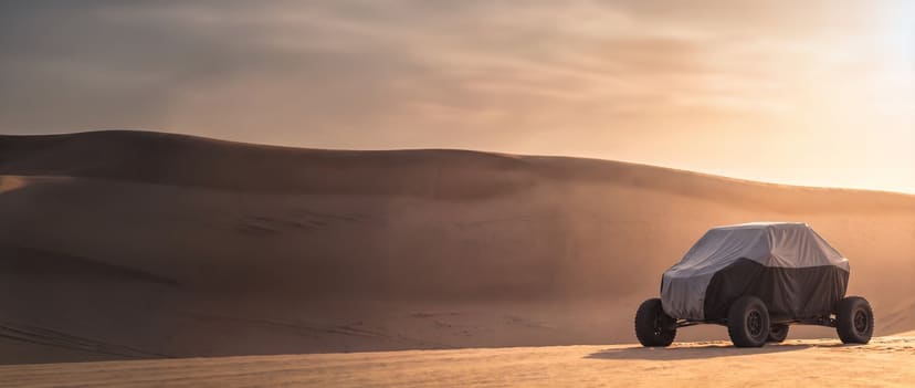 Two-tone cover on a sport side-by-side parked on calm sand dunes in low sun