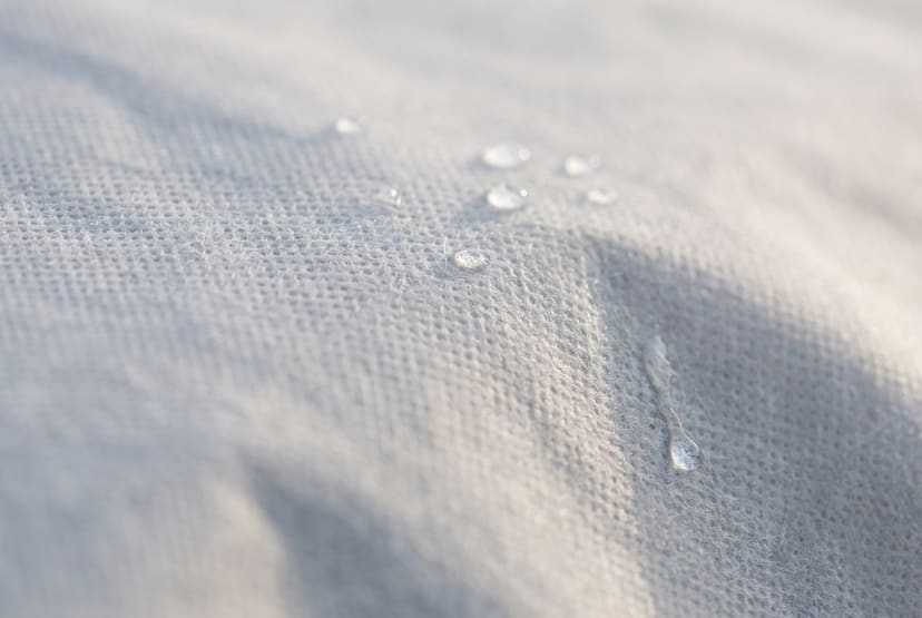 Close up of the light grey non-woven outer of a Weatherproof Max cover, with a few water beads resting on it