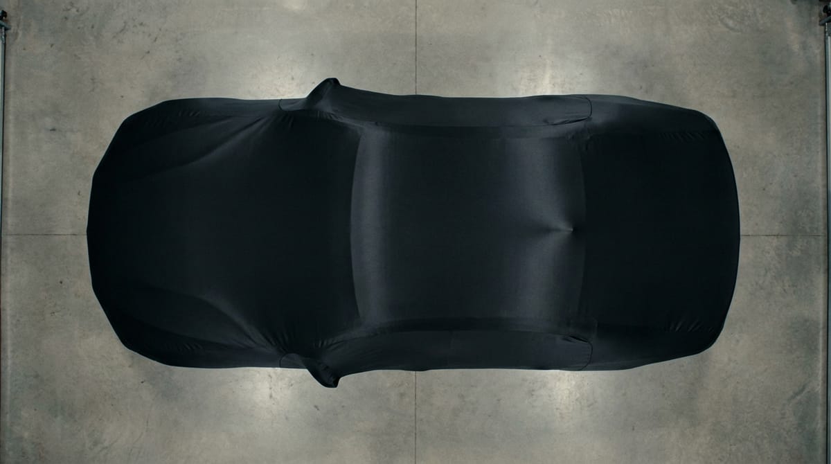 Black satin-finish cover on a car, garage concrete floor