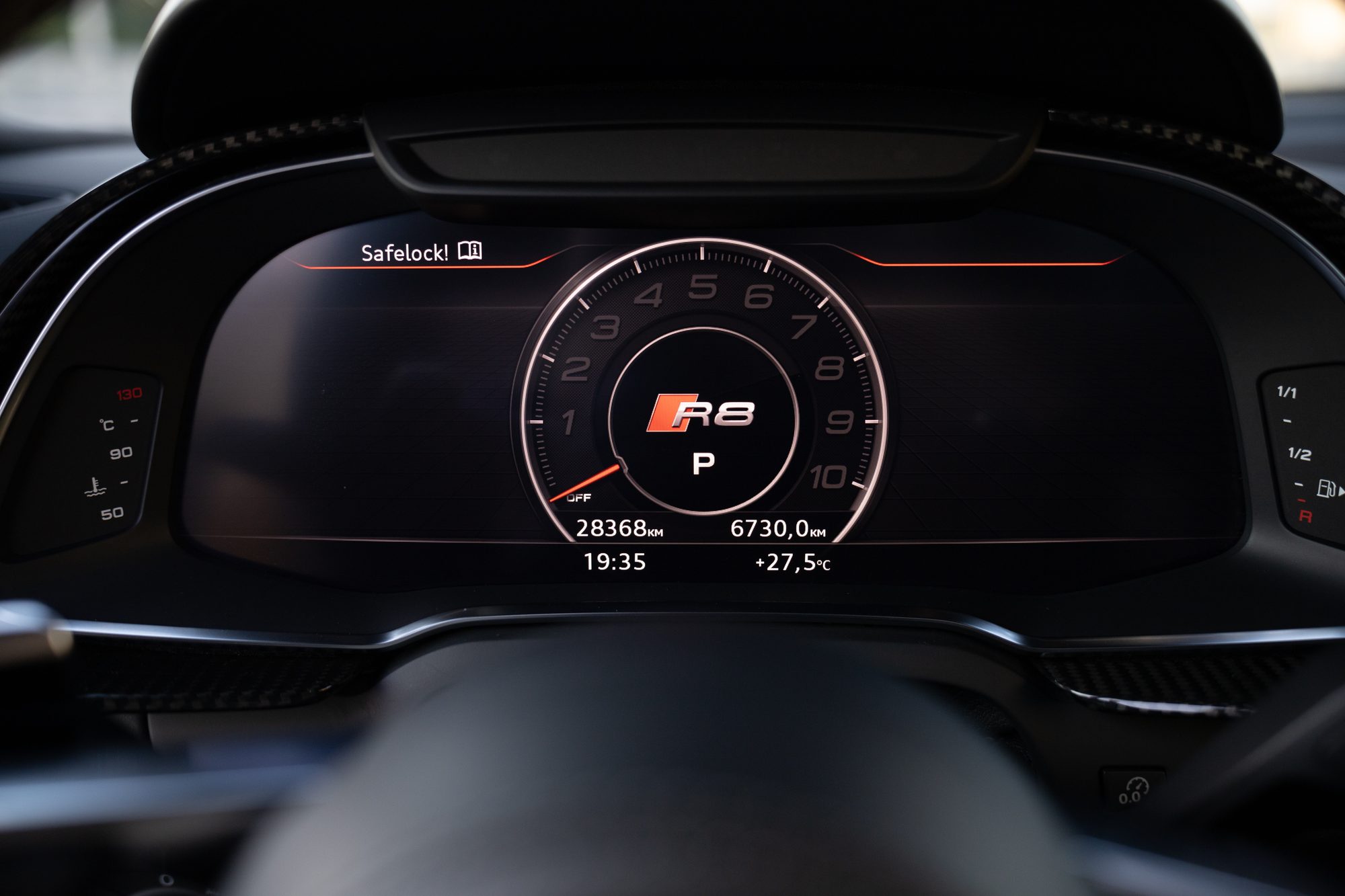 The Audi R8's digital instrument display, a tachometer reading to 10 around an R8 logo with the gearbox in Park, above odometer, trip, clock and outside-temperature readouts