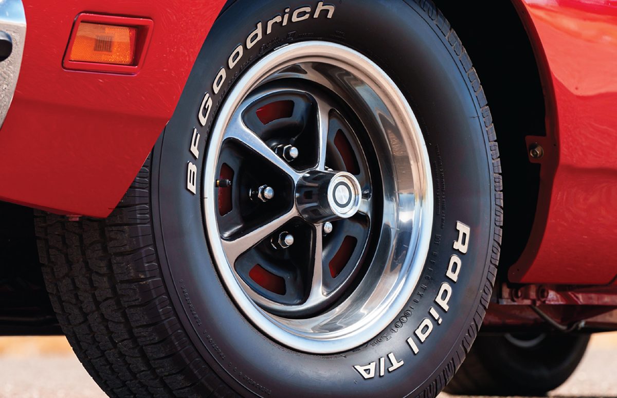 Close-up of the front wheel of a red classic car: a polished five-spoke wheel on a BFGoodrich Radial T/A tire with raised white lettering.