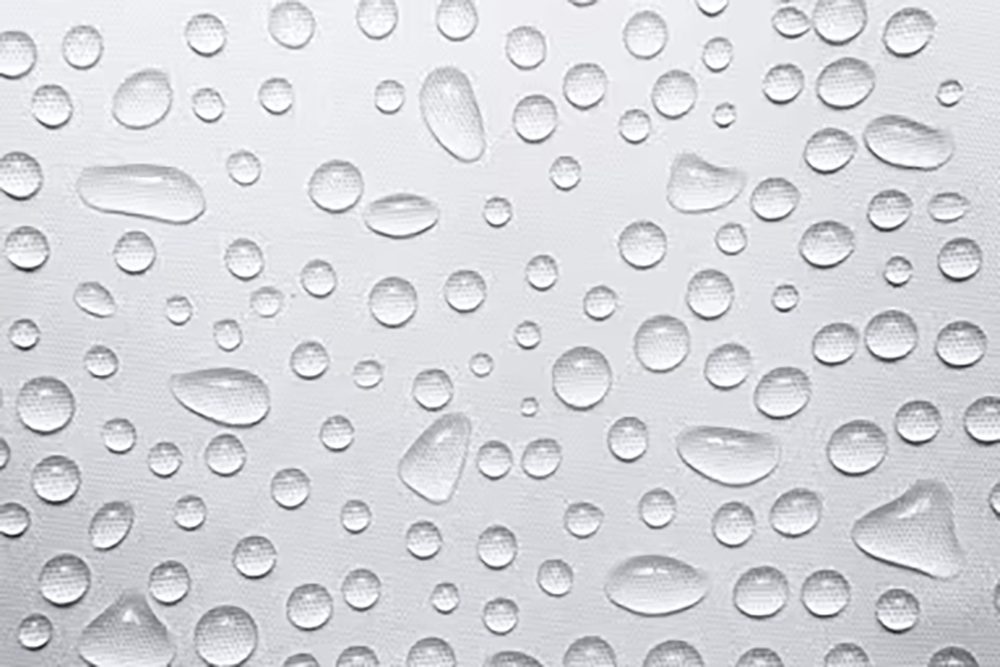 Close-up of water droplets beading on a light grey woven cover fabric