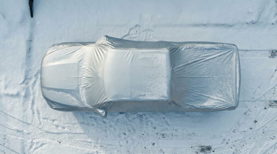 Overhead view of a covered pickup under real accumulated snow with tire tracks